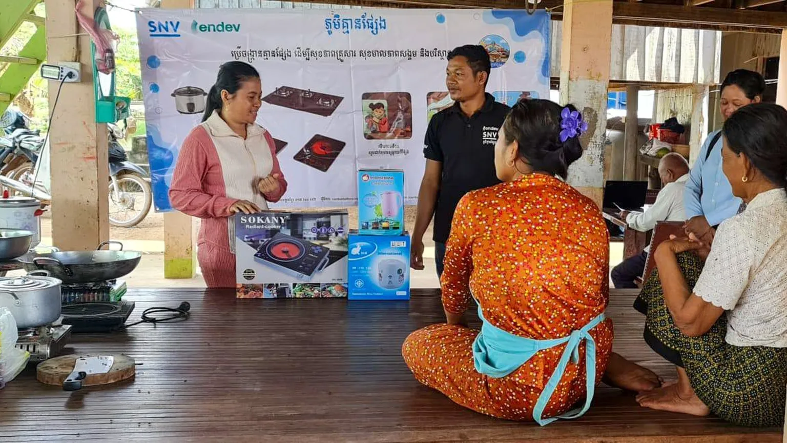 A woman presenting cookstoves to a group of people