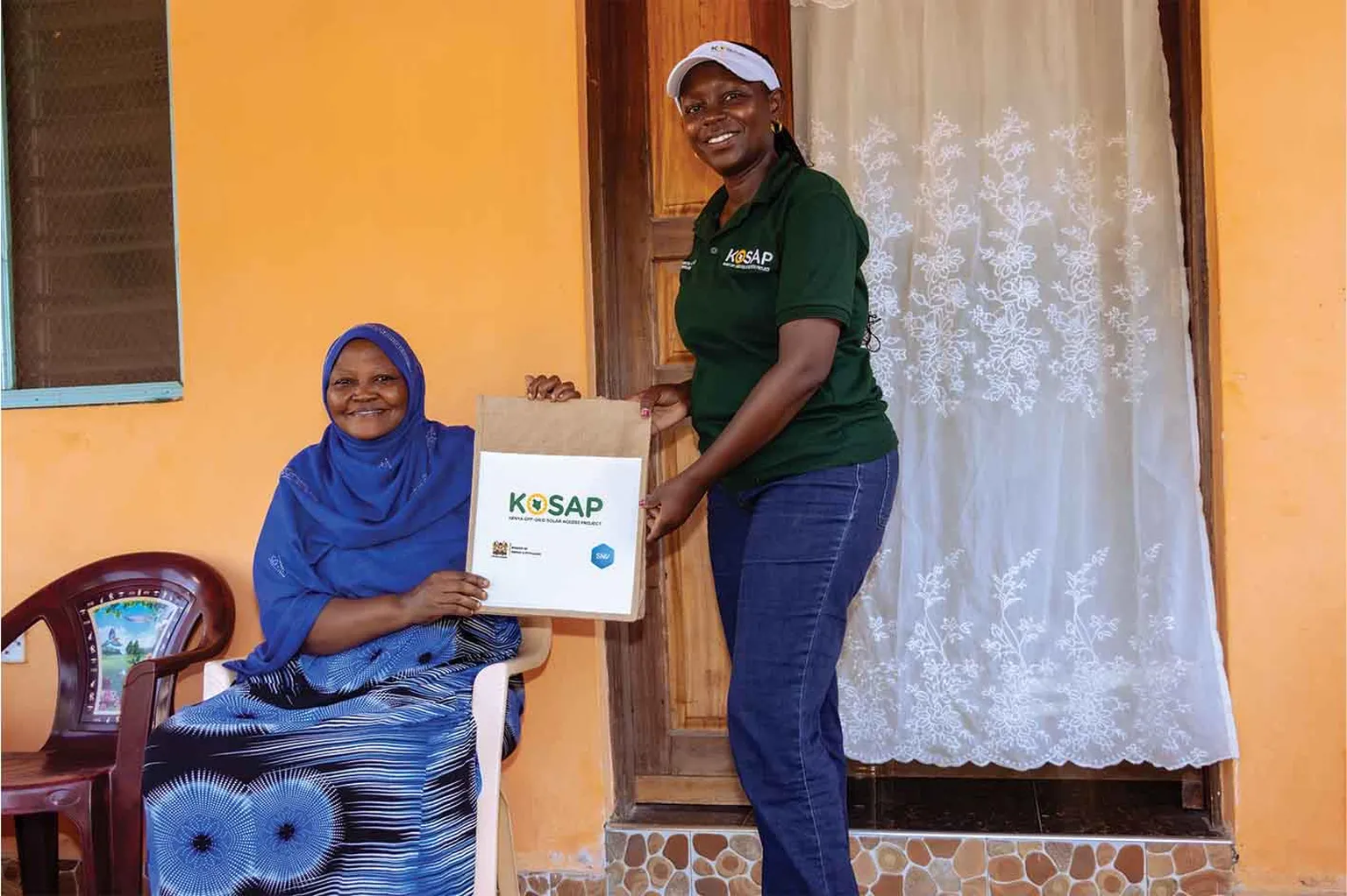 SNV field officer handing a bag to a household user of a jiko