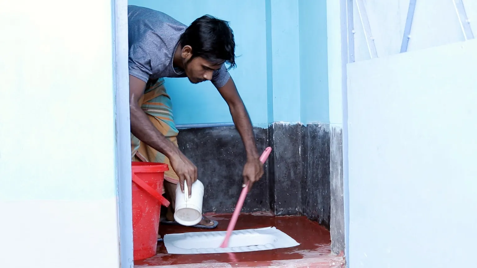 Toilet management committee member maintains public toilet in slum area in Bangladesh