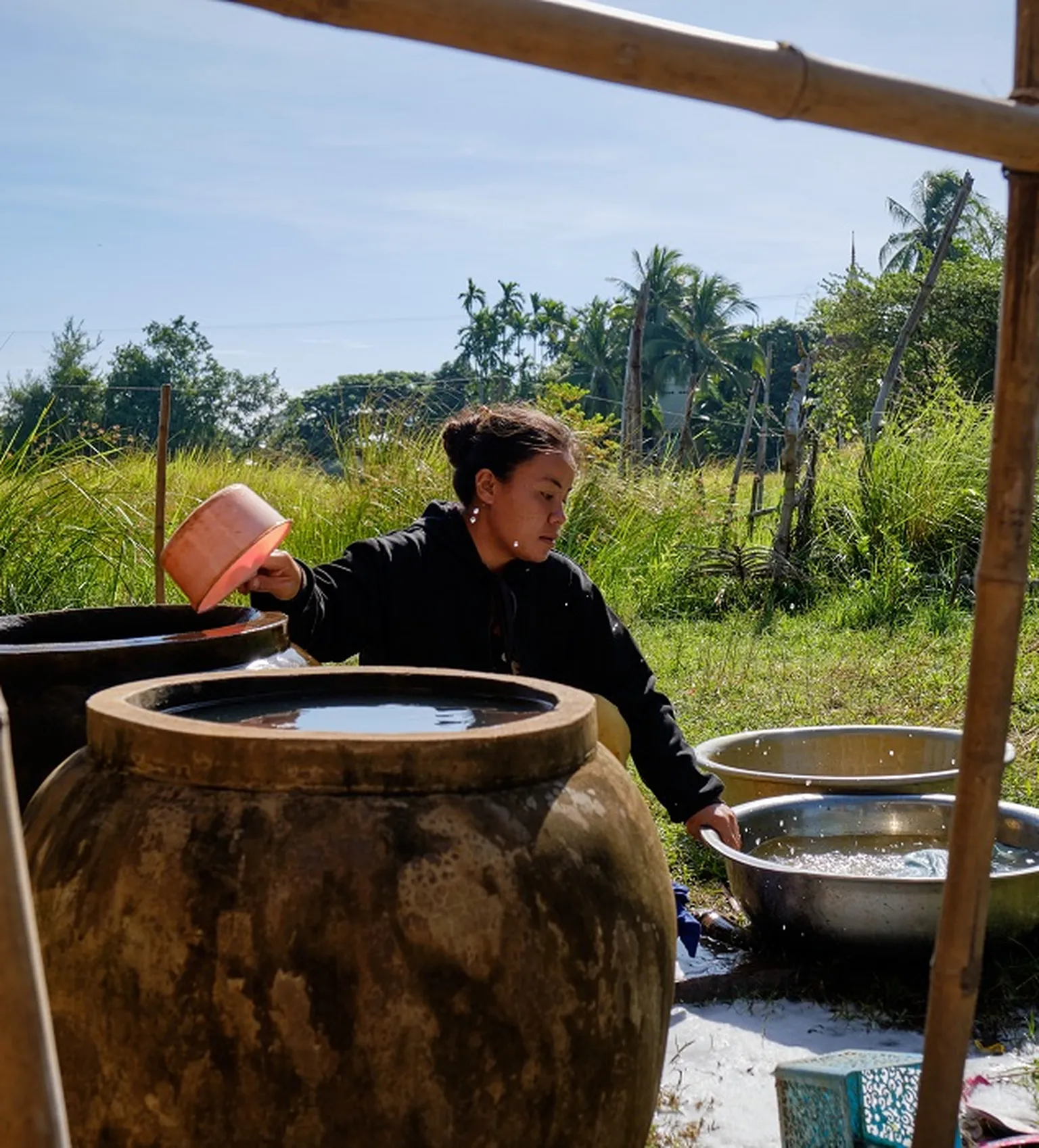 Champhone district resident drawing water stored in container (Bart Verweij for SNV)