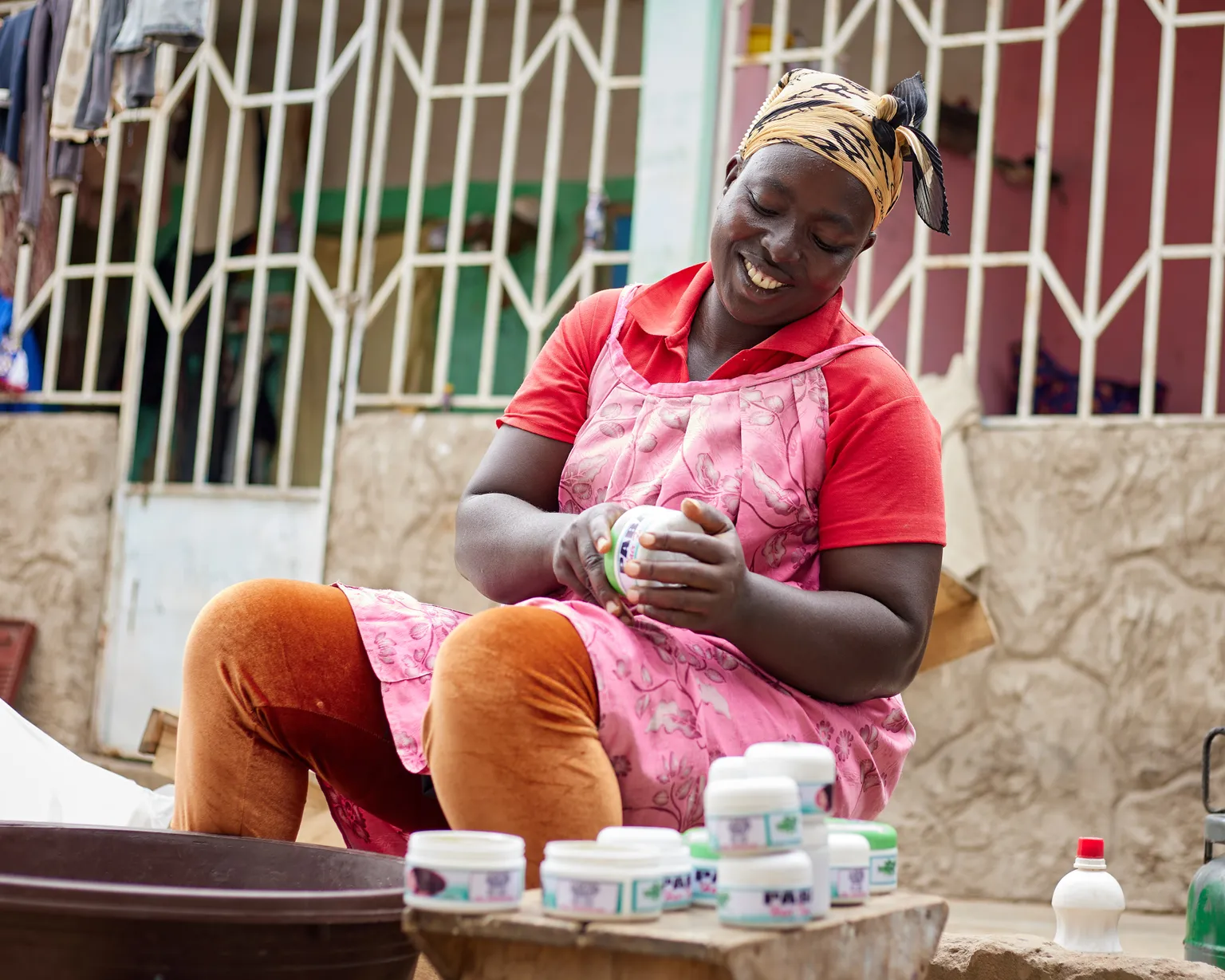 A woman sitting and holding creams she made as part of her enterprise