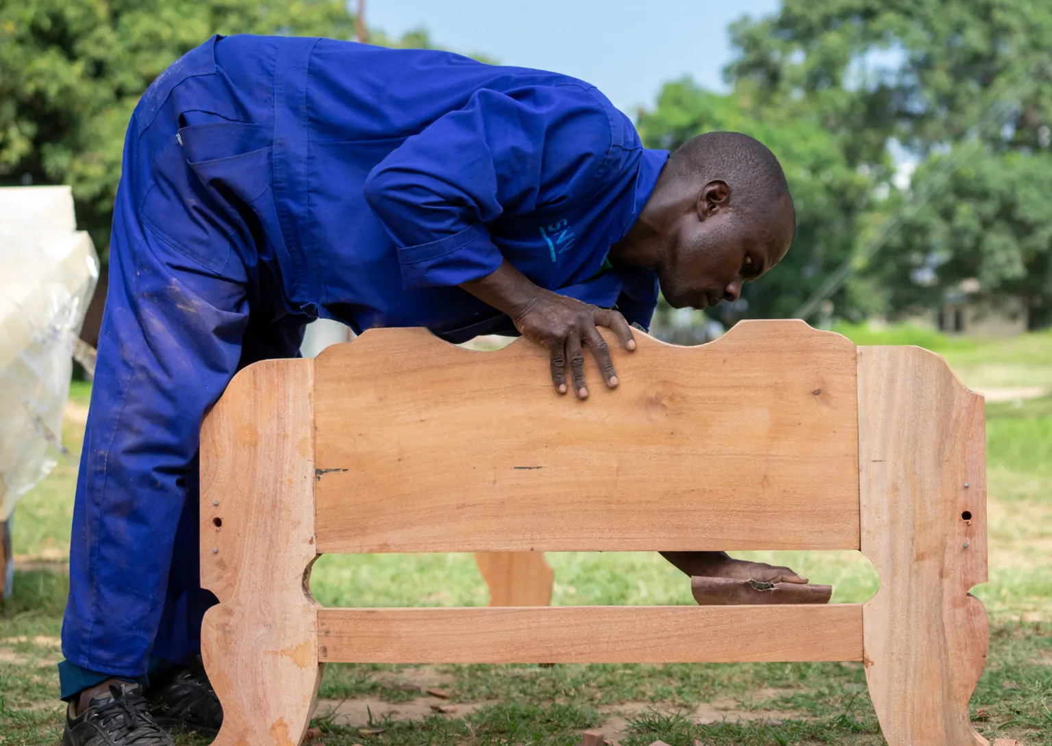 A man sands a wooden chair