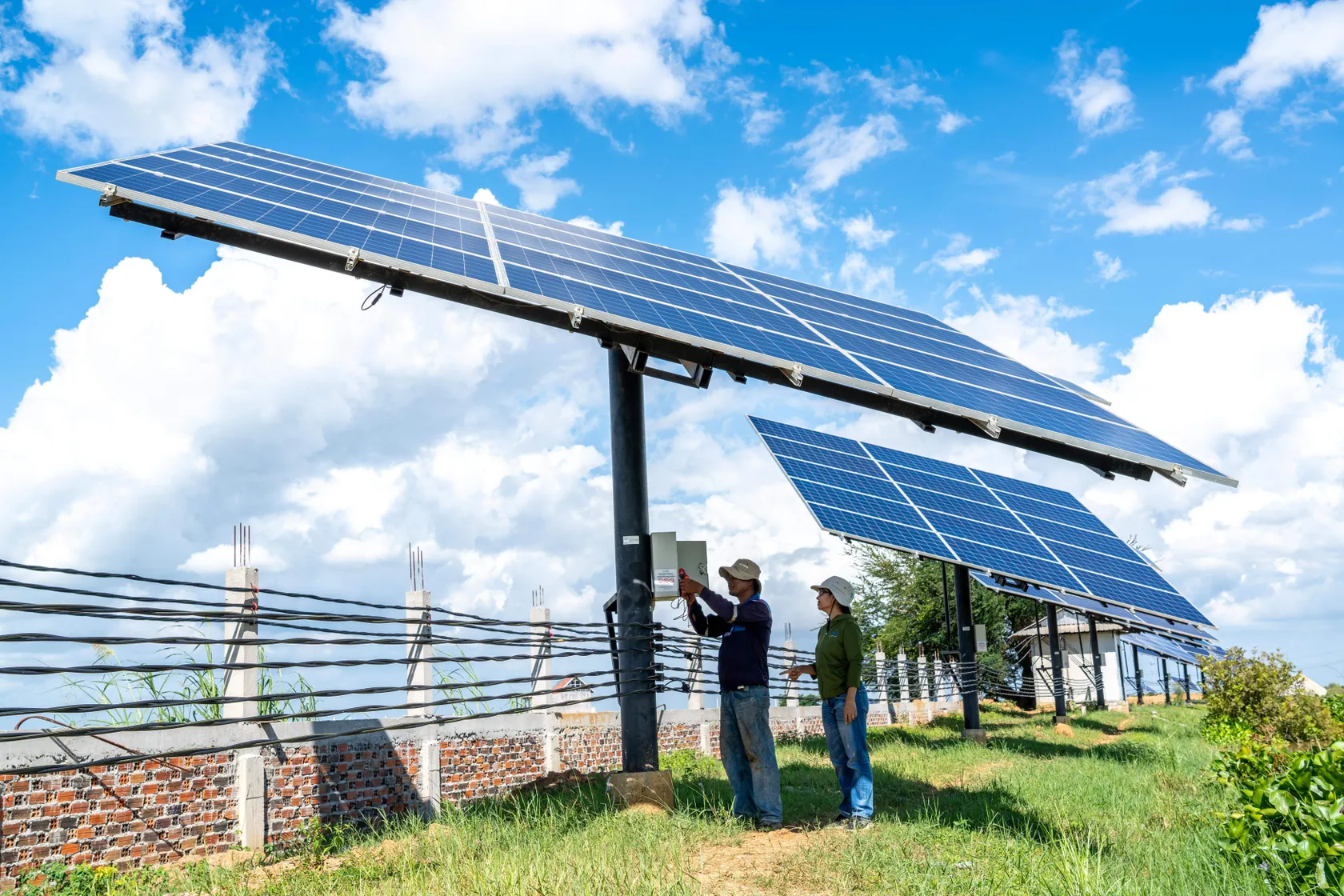 A man and woman work on a large solar panel