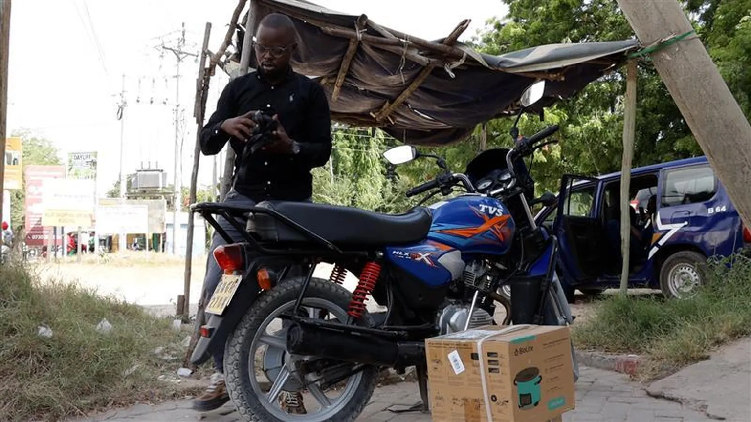 Stephene in Kenya posing for a photo next to his bike and clean cooker